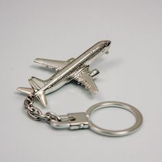 an airplane keychain is shown on a white surface with a metal chain attached to it