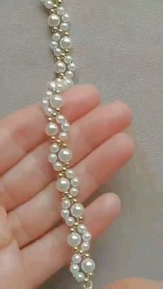 a hand holding a long white beaded necklace