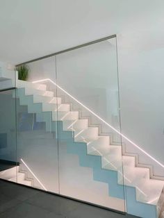 a glass stair case with blue and white stairs in the background, along with a potted plant