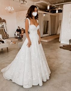 a woman in a white wedding dress wearing a face mask while looking at the camera