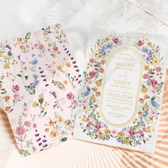 two wedding cards with floral designs on them, one is pink and the other is yellow