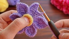 a person holding a crochet flower in their left hand and knitting the petals