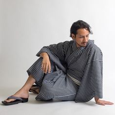 a man sitting on the ground wearing a black and white striped outfit