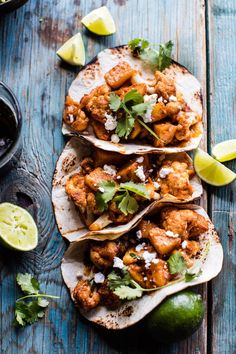 chicken tacos with cilantro and limes on a blue wooden table next to salsa