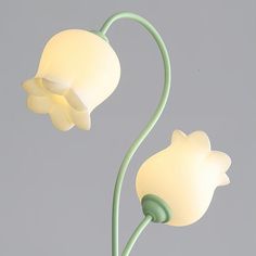 two white flowers with green stems on a gray background in the shape of a flower