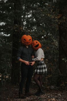 two people wearing pumpkin heads in the woods