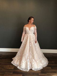 a woman in a wedding dress standing on the floor with her hands behind her back