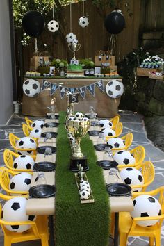 a long table with soccer balls and trophies on it is set up for a party