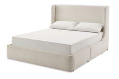 an upholstered bed with white linens and pillows