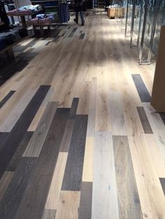 a person walking down a wooden floor in an office building with lots of glass walls