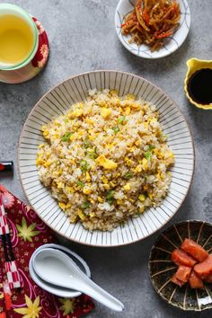 a plate with rice and vegetables on it next to two bowls filled with sauces