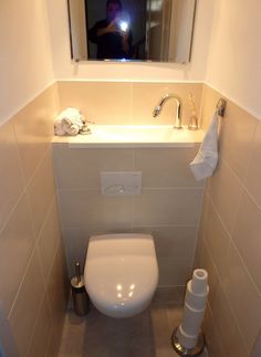 a white toilet sitting under a bathroom mirror