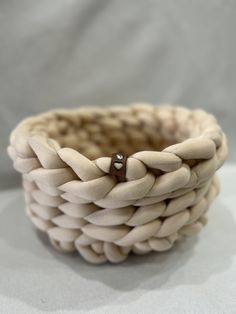 a close up of a woven basket on a white tablecloth with a ring in the middle