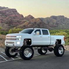 a white truck parked in a parking lot with mountains in the backgrouund