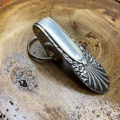 a metal object sitting on top of a piece of wood next to a keychain