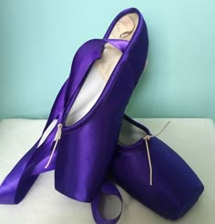 pair of purple ballet shoes on white surface with blue wall in the backgroud