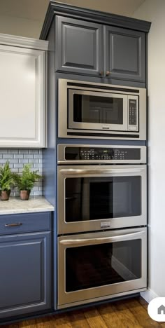 an oven built into the side of a wall in a kitchen with blue cabinets and wood floors