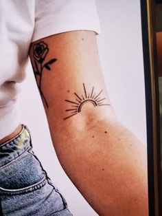 a woman's arm with a tattoo on it, and the sun behind her