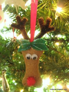 an ornament hanging from a christmas tree decorated with reindeer noses and green leaves