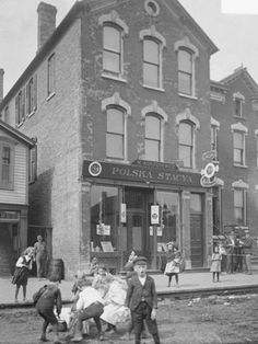 an old black and white photo of children playing in front of a building with people standing outside