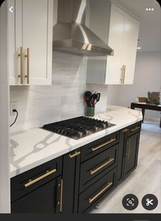 a kitchen with marble counter tops and gold trim on the oven hood, along with white cabinets