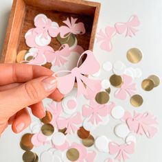 a person holding a pink and white paper butterfly in front of some confetti