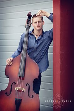 a man standing next to a cello leaning against a wall