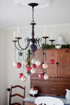 a chandelier with christmas ornaments hanging from it's centerpiece in a dining room