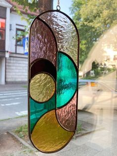 a stained glass sun catcher hanging on a window sill in front of a building