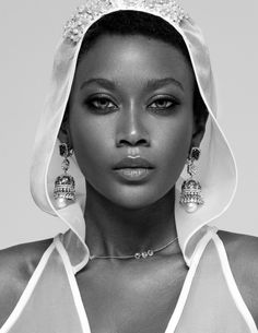 a woman in a white dress and veil with earrings on her head is posing for the camera