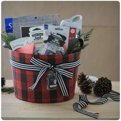 a red and black plaid christmas basket with pine cones, candy canes and other holiday items