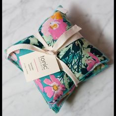 a small pouch with a tag tied to it sitting on a marble counter top next to a white and pink flowered napkin