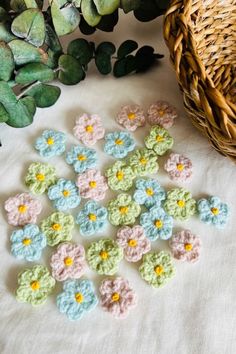 small crocheted flowers sitting on top of a table next to a basket and plant