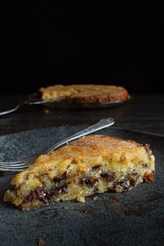 a piece of cake sitting on top of a black plate next to a knife and fork