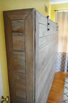 an old wooden bed frame in the corner of a room with yellow walls and wood flooring