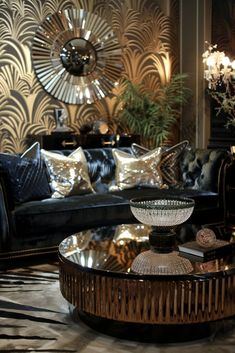 a living room with black couches and gold accents on the walls, coffee table