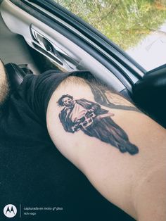 a man with a tattoo on his arm sitting in a car