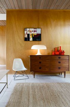 a living room with a white chair and wooden paneled wall in the back ground