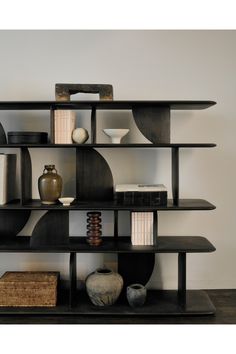 a shelf with books, vases and other items on it in a living room