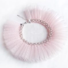 a pink beaded bracelet with pearls and beads hanging from it's end on a white background