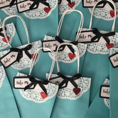 blue paper bags with red hearts and black ribbon tied to them, each bag has a name tag that says take me