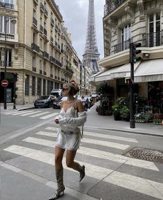 a woman is running down the street in front of the eiffel tower