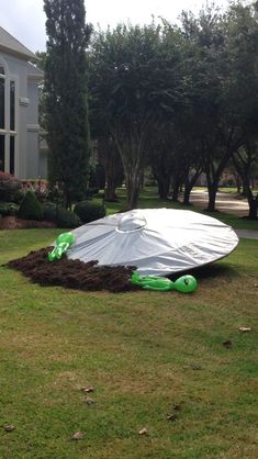 a large white umbrella sitting on top of a lush green field in front of a house