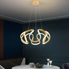 a modern chandelier hanging over a round dining table in a room with blue walls