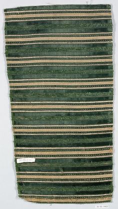 a piece of cloth that has been woven with strips of green and brown yarn on it