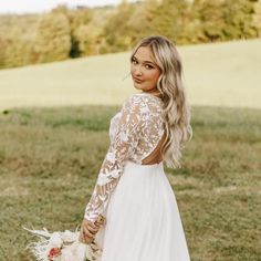 a woman in a white dress holding a bouquet and wearing a long sleeved wedding dress