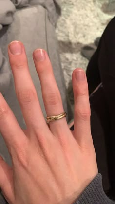 a woman's hand with a gold wedding ring on it, next to a rock