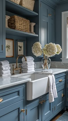 a kitchen with blue cabinets and white flowers in a vase on the sink countertop