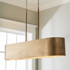 a wooden light fixture hanging from a ceiling in a room with white walls and windows