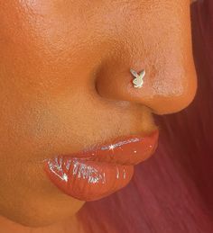 a woman with orange lipstick and piercings on her nose